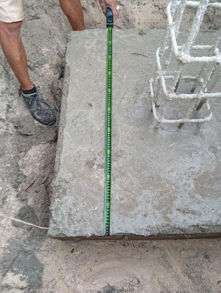 A column footing measured with a tape, steel reinforcement in place