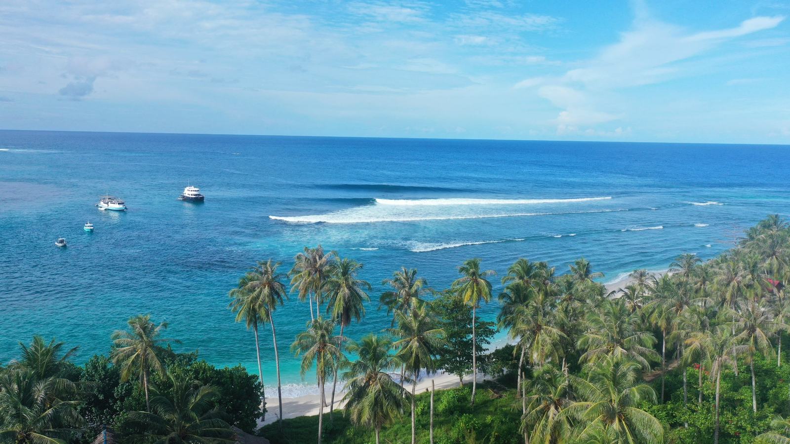Kapal surf charter berlabuh dekat ombak karang di Mentawai